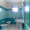 Bagno con piastrelle verdi e finestra aperta.