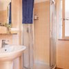 Bagno con doccia angolare in vetro, lavabo e asciugamano blu appeso sopra.