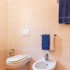 Bagno con WC sospeso, bidet e asciugamani blu su porta asciugamani.