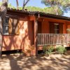Facciata di una casa arancione con finestre e persiane, circondata da alberi.