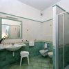 Bagno con doccia angolare e piastrelle verdi.