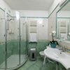 Bagno con doccia circolare e piastrelle verdi.