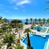 Piscina e mare con palme, cielo blu.