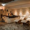 Area relax con lettini e parete in pietra illuminata.