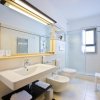 Un bagno moderno con lavabo, bidet e doccia. Piastrelle chiare e ampia specchiera.