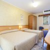 Camera d'albergo con due letti matrimoniali, scrivania, TV e finestra.