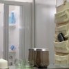 Una doccia con portasapone e un organizer a muro. Candele e bicchieri sul piano.