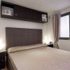 Camera da letto con letto matrimoniale, testiera imbottita e armadietti scuri.
