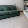 Un soggiorno con divano verde, tavolino apparecchiato e angolo cottura.