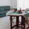 Tavolo da pranzo apparecchiato, divano verde sullo sfondo.