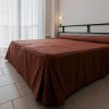 Camera da letto con letto matrimoniale, copriletto marrone e sedia coordinata.