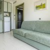 Soggiorno con divano verde chiaro, cucina e porta d'ingresso.