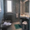 Bagno con bidet, asciugamani bianchi, tappeto verde e finestra luminosa.
