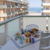 Balcone con tavolo apparecchiato, sedie bianche, vista sul mare e palazzi.
