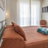 Letto matrimoniale con asciugamani arrotolati, TV a parete e sedia vicino a una finestra ampia.