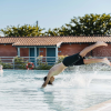 Ragazzo si tuffa in piscina vicino a edifici di legno.