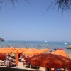 Spiaggia affollata con ombrelloni arancioni.