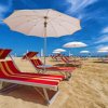 Spiaggia con lettini rossi e ombrelloni bianchi.