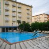 Piscina esterna con scivolo, circondata da lettini.