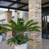 Ingresso hotel con piante in vaso e colonne.