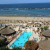 Piscina e spiaggia con ombrelloni vicino al mare.