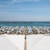 Spiaggia con file di ombrelloni blu e bianchi.