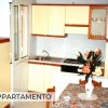 Cucina con mobile bianco e arancione, tavolo con fiori.