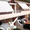 Edificio con terrazze e tende bianche a righe.