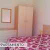 Camera da letto con armadio bianco e copriletto rosso.
