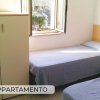 Camera con due letti singoli, armadio e finestra aperta.