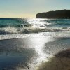 Mare con onde e promontorio al tramonto.