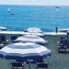 Ombrelloni su spiaggia con vele in mare.