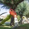 Uno scivolo colorato in un parco con grandi alberi.