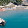 Spiaggia con ombrelloni colorati e promontorio roccioso.