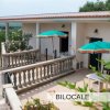 Terrazza con ombrelloni verdi e panoramica campagna.