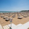 Spiaggia sabbiosa con lettini e ombrelloni bianchi sotto un cielo sereno.