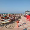 Spiaggia affollata con ombrelloni e lettini.