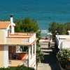Casa con terrazza vista mare, circondata da alberi.