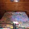 Letto matrimoniale in legno con coperta colorata.